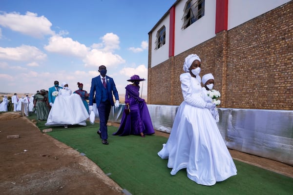 A man with his wife and two of his brides walk, during mass Easter weddings for 3,000 people, some polygamous, at the International Pentecost Holiness Church in Heidelberg, east of Johannesburg, South Africa, Sunday, April 20, 2025. (AP Photo/Themba Hadebe)