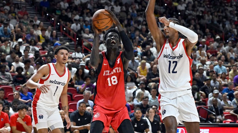 Atlanta Hawks forward Mouhamed Gueye (18) shoots between Washington Wizards guard Johnny Davis (1) and center Alex Sarr (12) during the first half of an NBA summer league basketball game Friday, July 12, 2024, in Las Vegas. (AP Photo/David Becker)