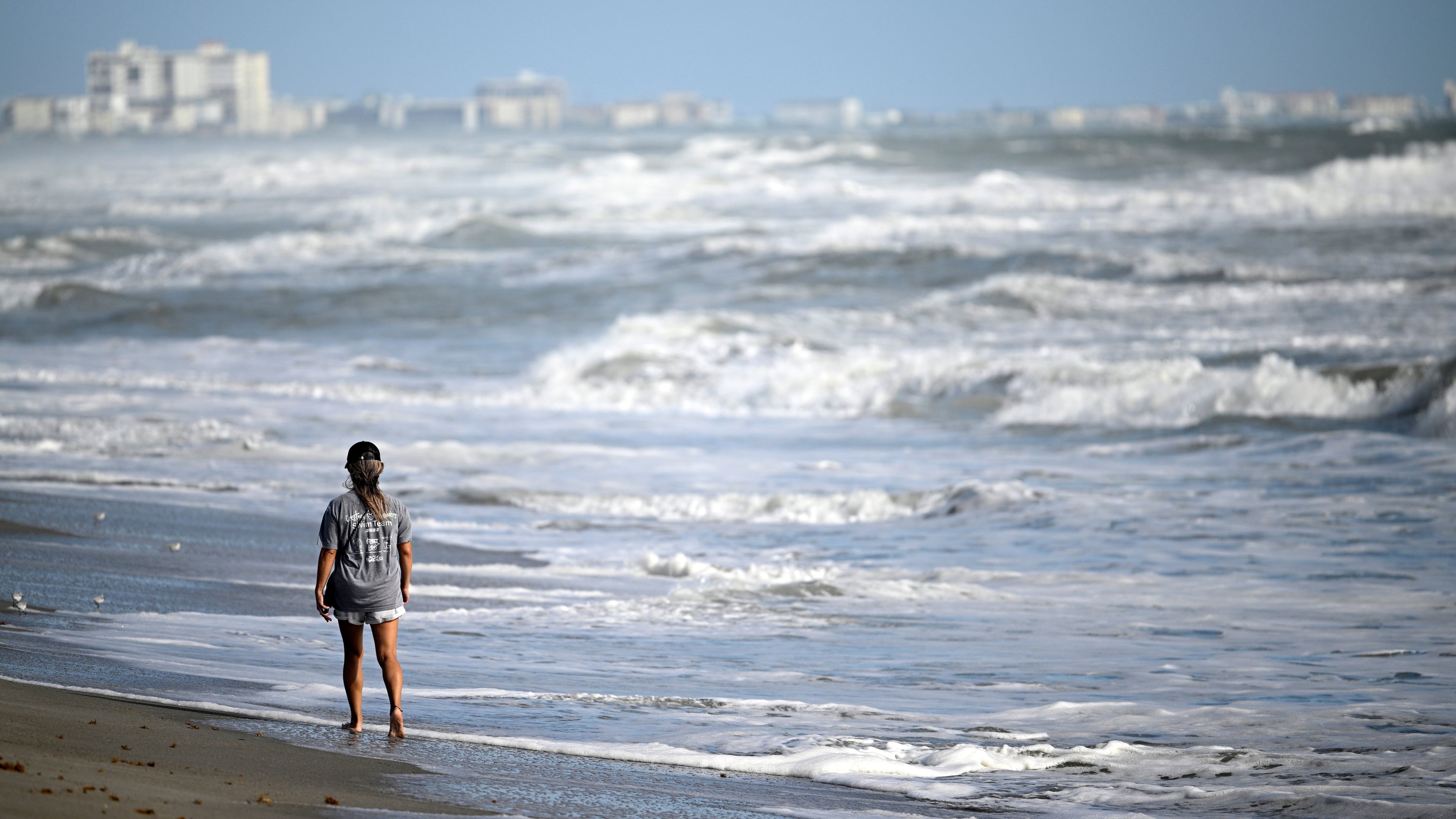 Maiko Russell walks along the sand as Tropical Imelda passes offshore, kicking up the surf at Blockhouse Beach, Monday, Sept. 29, 2025, at Patrick Space Force Base, Fla. (AP Photo/Phelan M. Ebenhack)