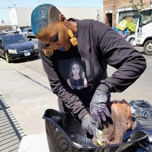This photo provided by Melissa Acedera shows Shirley Raines washing a person's hair in Skid Row, 2018, in Los Angeles. (Melissa Acedera via AP)
