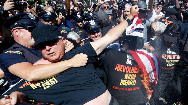 FILE - In this July 20, 2016 file photo, a law enforcement officer takes Gregory "Joey" Johnson into custody after he started to burn an American flag in Cleveland, during the third day of the Republican convention. President-elect Donald Trump said Tuesday that anyone who burns an American flag should face unspecified "consequences," such as jail or a loss of citizenship _ a move that was ruled out by the Supreme Court nearly three decades ago. (AP Photo/John Minchillo)