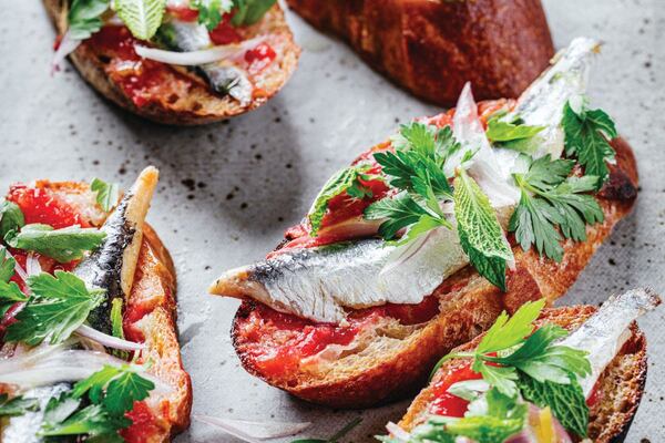 Five toast slices of garlic-rubbed toast loaded with fresh tomatoes, olive oil, and boquerones.