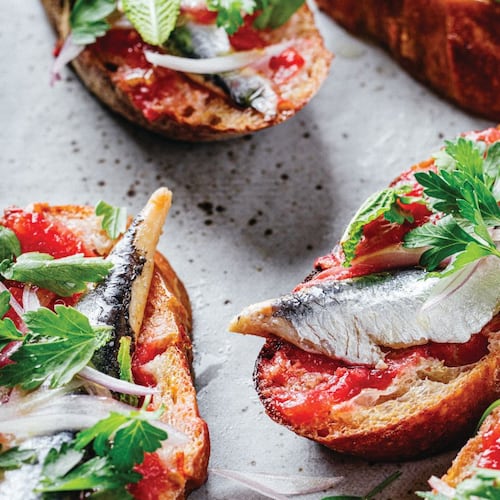 Five toast slices of garlic-rubbed toast loaded with fresh tomatoes, olive oil, and boquerones.