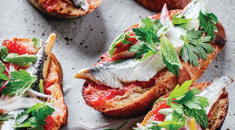 Five toast slices of garlic-rubbed toast loaded with fresh tomatoes, olive oil, and boquerones.