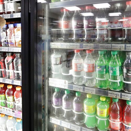 FILE - A shop owner reaches into a drink display refrigerator at his convenience store in Kent, Wash., Oct. 1, 2018. (AP Photo/Elaine Thompson, File)