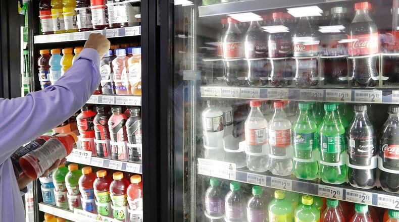 FILE - A shop owner reaches into a drink display refrigerator at his convenience store in Kent, Wash., Oct. 1, 2018. (AP Photo/Elaine Thompson, File)