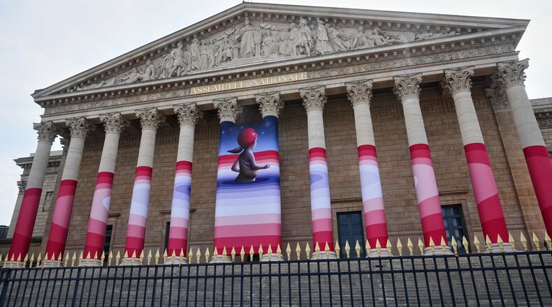 The French National Assembly is draped with the artwork "Marianne rêve" ("Marianne Dreams") by French street artist Seth, depicting Marianne the symbol of the French Republic, before lawmakers vote later on final approval of a bill allowing adults with incurable illnesses to receive lethal medication, in Paris, Wednesday, July 15, 2026. (AP Photo/Michel Euler)