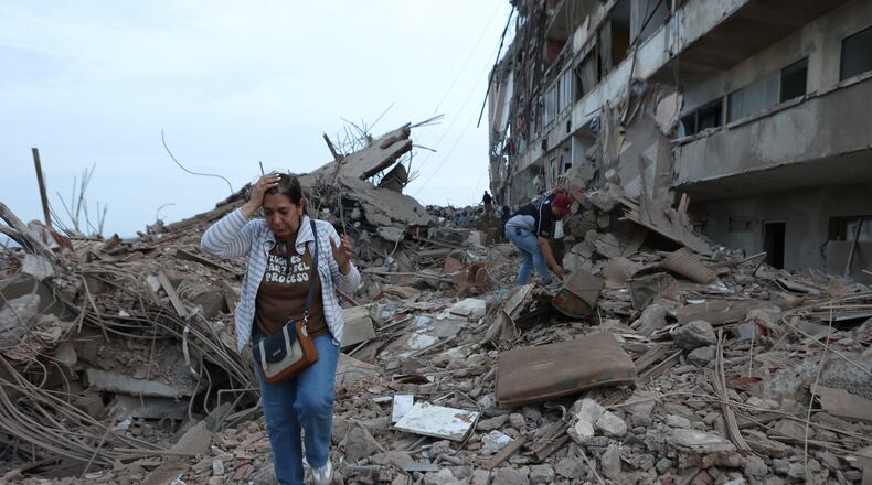 Residents walk among the rubble of building damaged in earthquakes the previous day in Catia La Mar, Venezuela, Thursday, June 25, 2026. (AP Photo/Pedro Mattey)