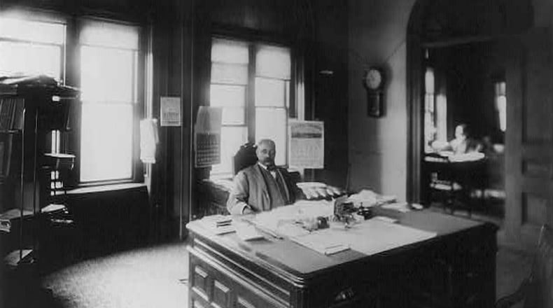 Henry A. Rucker, internal revenue collector, seated at large desk in an Atlanta office.