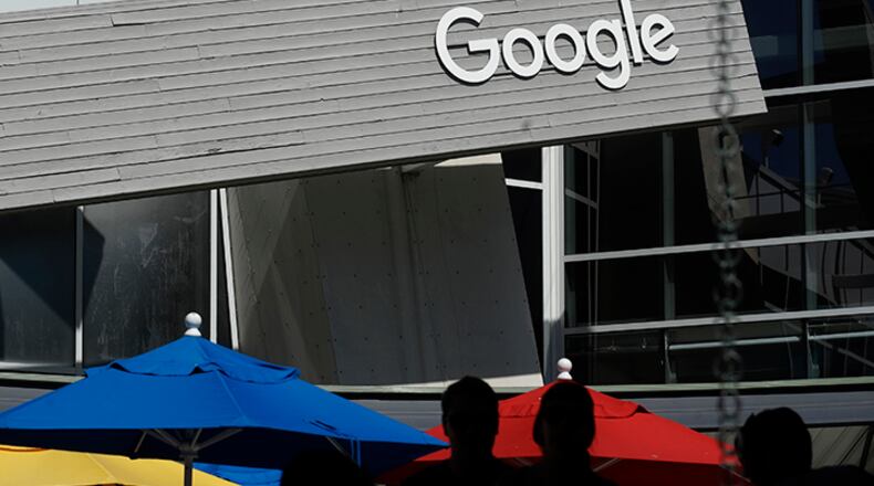 People walk by a Google sign on the campus in Mountain View, California. Google co-founders Larry Page and Sergey Brin are relinquishing control of parent company Alphabet to current Google CEO Sundar Pichai.