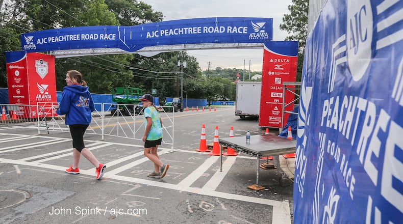 Mackenzie and Addison Brawner help set up Monday at the finish line of The Atlanta Journal-Constitution Peachtree Road Race at Piedmont Park. Thousands of runners will hit the pavement Tuesday. JOHN SPINK / JSPINK@AJC.COM