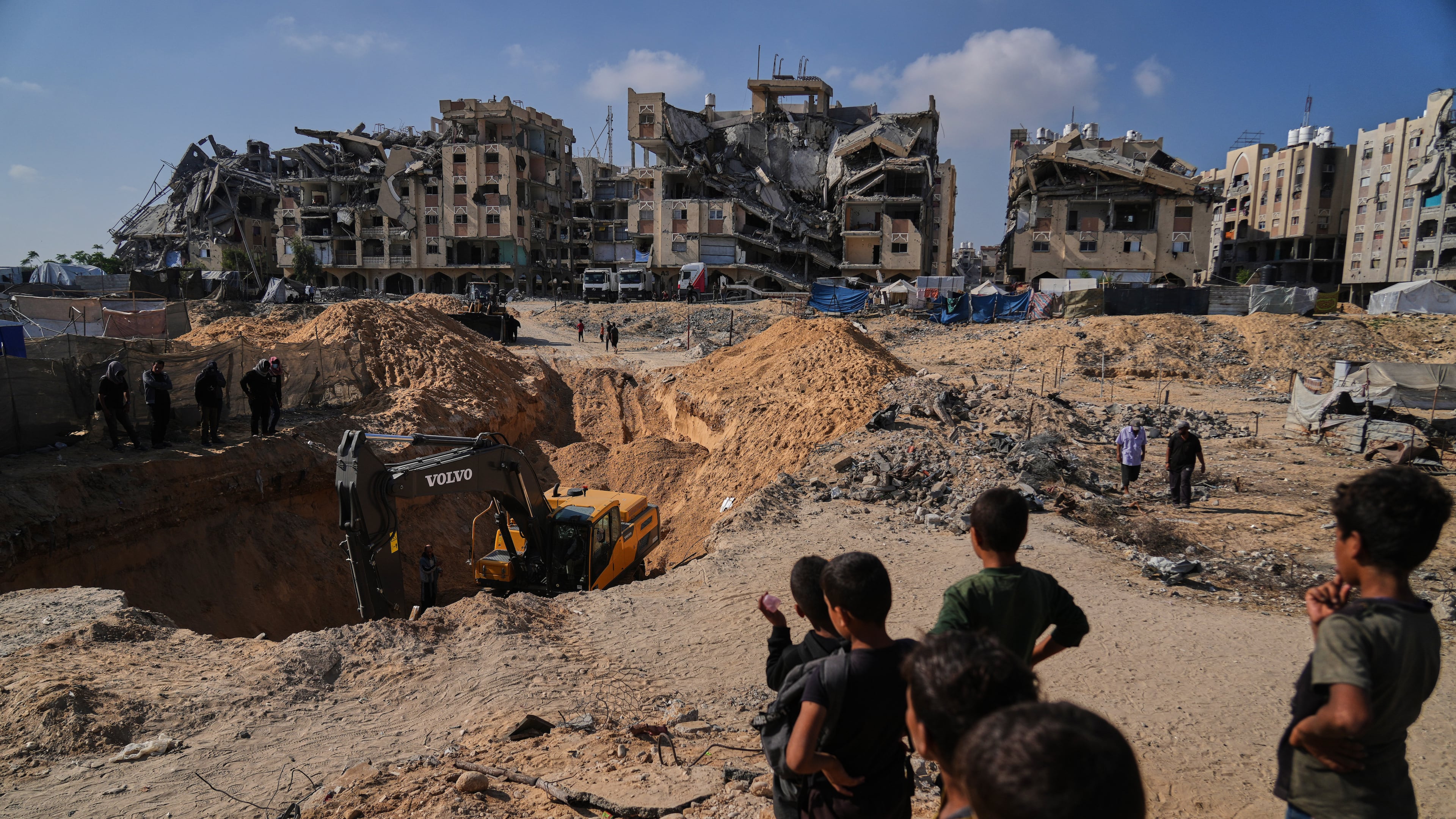 Palestinians watch as Egyptian machinery and workers search for the bodies of hostages in Hamad City, Khan Younis, in the southern Gaza Strip, Tuesday, Oct. 28, 2025. (AP Photo/Abdel Kareem Hana)