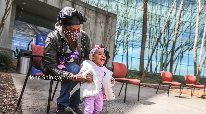 Elizabeth Grisby holds a beaming Royalty Grisby, 1, outside DeKalb County police headquarters Friday before providing an update on the child's condition following her harrowing abduction the day before.