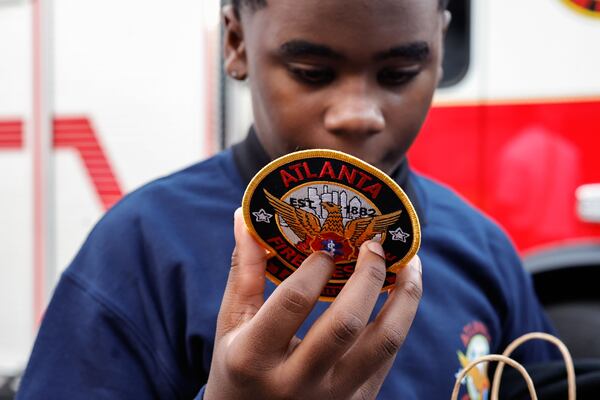 Johnny Jones checks out an Atlanta Fire Rescue patch gifted to him. The children reunited with their rescuers at the fire station on Thursday, Nov. 20, 2025. (Natrice Miller/AJC)
