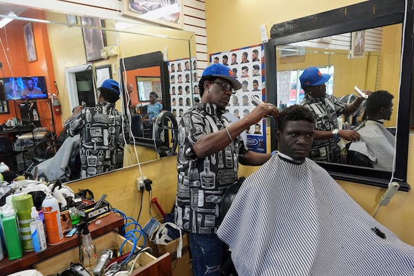 FILE - Creole-language news airs on a TV as barber Charlemagne Merilien cuts a client's hair inside Els Beauty Salon in Miami's Little Haiti neighborhood, June 6, 2025. (AP Photo/Rebecca Blackwell, File)