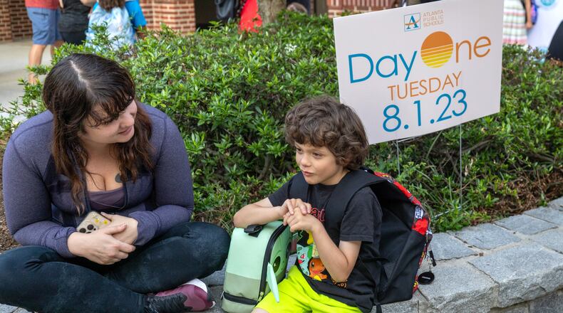 Ashley Simpson and her son Harrison, 7, sit outside Virginia-Highland Elementary, waiting for the first day of school to start Tuesday, Aug. 1, 2023. (Steve Schaefer/steve.schaefer@ajc.com)