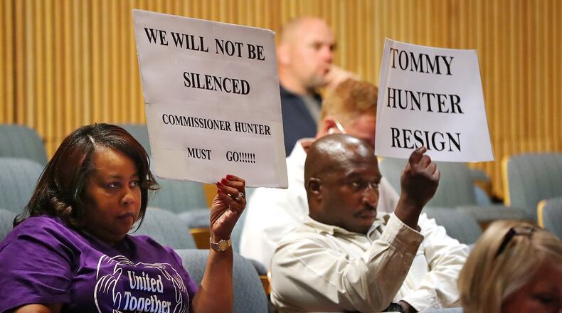 Gwinnett residents Phyllis Richardson and Michael Richardson (not related) hold signs while more protesters demand the resignation of Tommy Hunter during the Gwinnett County Board of Commissioners public hearing session on Tuesday. Curtis Compton/ccompton@ajc.com