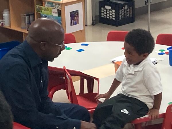 U.S. Sen. Raphael Warnock ties a boy's shoe during his visit Monday to the Savannah Head Start program.  (Adam Van Brimmer/ adam.vanbrimmer@ajc.com)