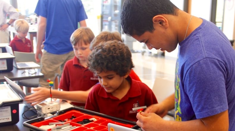 A junior from Holy Innocents' Upper School works with a kindergartner from the Primary School inside of a STEM robotics lab. Holy Innocents' Episcopal School is hosting its "STEMsational" camp on Saturday, Nov. 5.