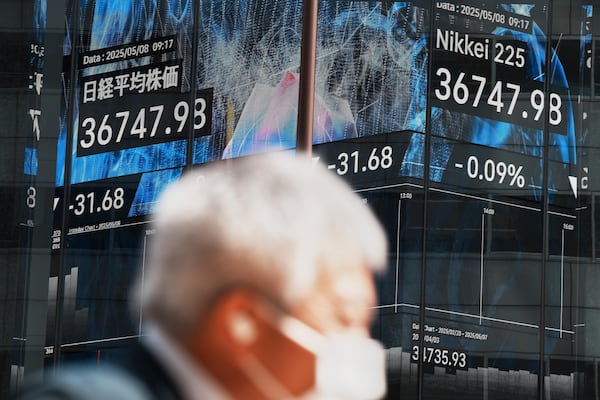 A person walks in front of an electronic stock board showing Japan's Nikkei index at a securities firm Thursday, May 8, 2025, in Tokyo. (AP Photo/Eugene Hoshiko)
