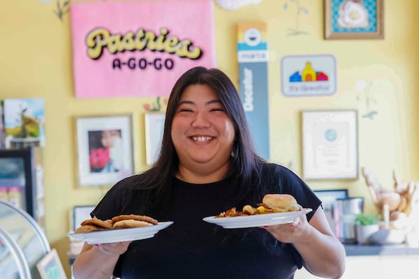 Pastries A Go Go owner, Adriana Park holds a plate of assorted cookies and a Bacon and Eggs Biscuit with home fries at her location in Downtown Decatur. Pastries A Go Go sometimes offers salt bread as a special. (Miguel Martinez/AJC)