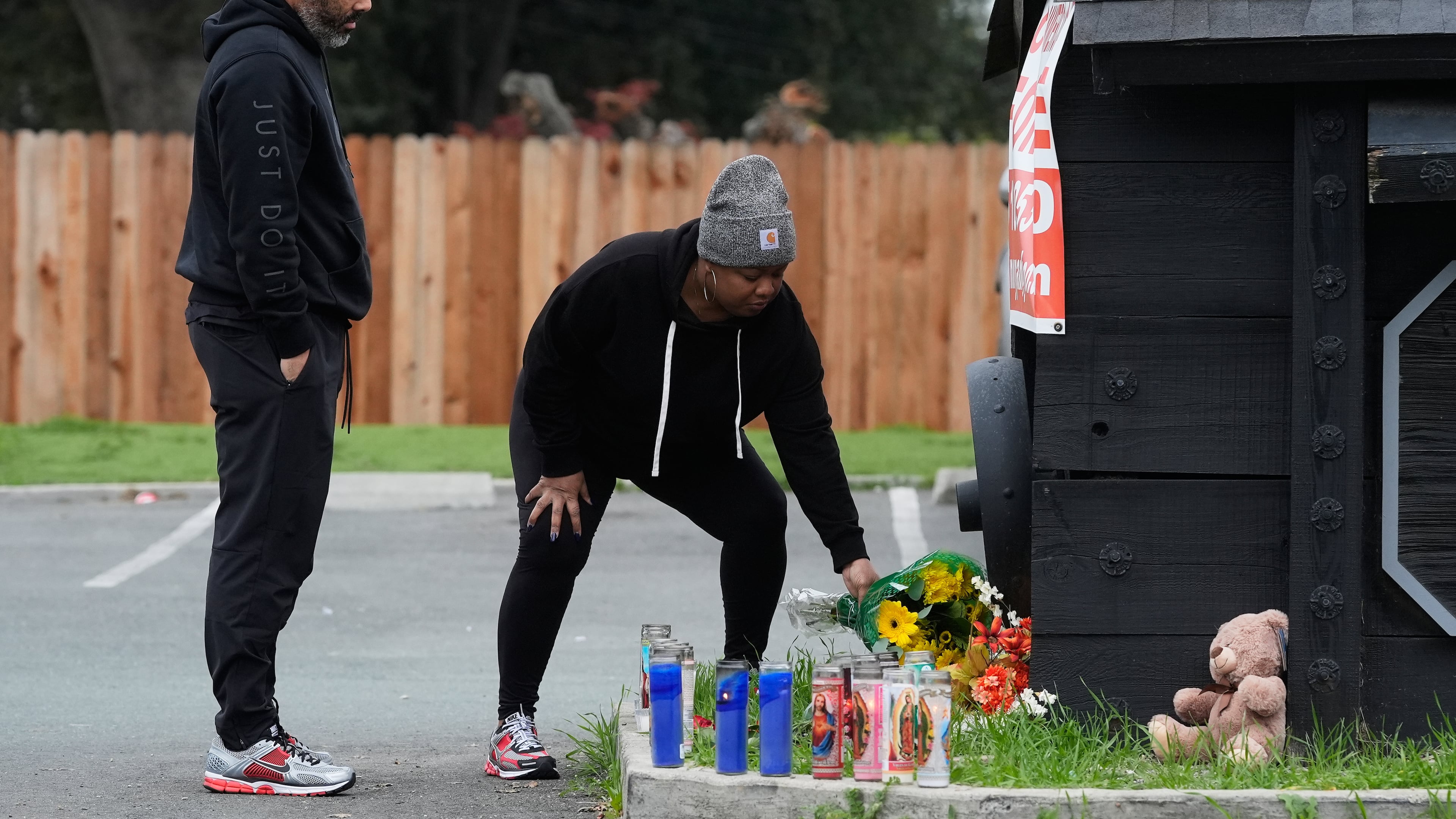 Aundre Smith, left, watches as Genesis Smith places flowers near the scene of a mass shooting on Saturday at a banquet hall in Stockton, Calif., Monday, Dec. 1, 2025. (AP Photo/Jeff Chiu)