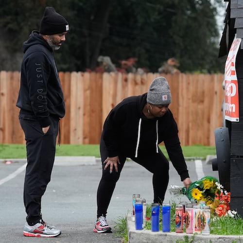 Aundre Smith, left, watches as Genesis Smith places flowers near the scene of a mass shooting on Saturday at a banquet hall in Stockton, Calif., Monday, Dec. 1, 2025. (AP Photo/Jeff Chiu)