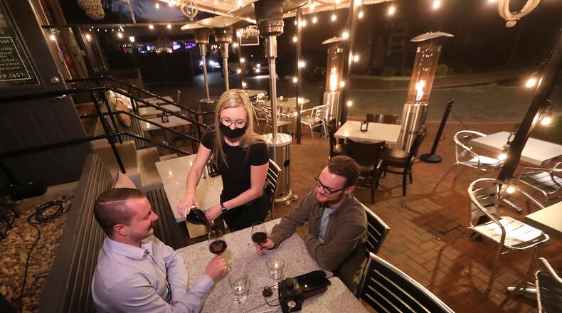 Canton St. Social manager Lillie Parnell serves Marcus Nash (right) and Royce Binnion wine as they enjoy the patio all to themselves  Owner Meredith Longwith opened the Roswell business last August figuring the health crisis would last only a few more months but has considered closing permanently as the pandemic continues. After seeing increased reservation bookings over the last several weeks she has some optimism about the future, but is still operating in the negative. CREDIT: Curtis Compton