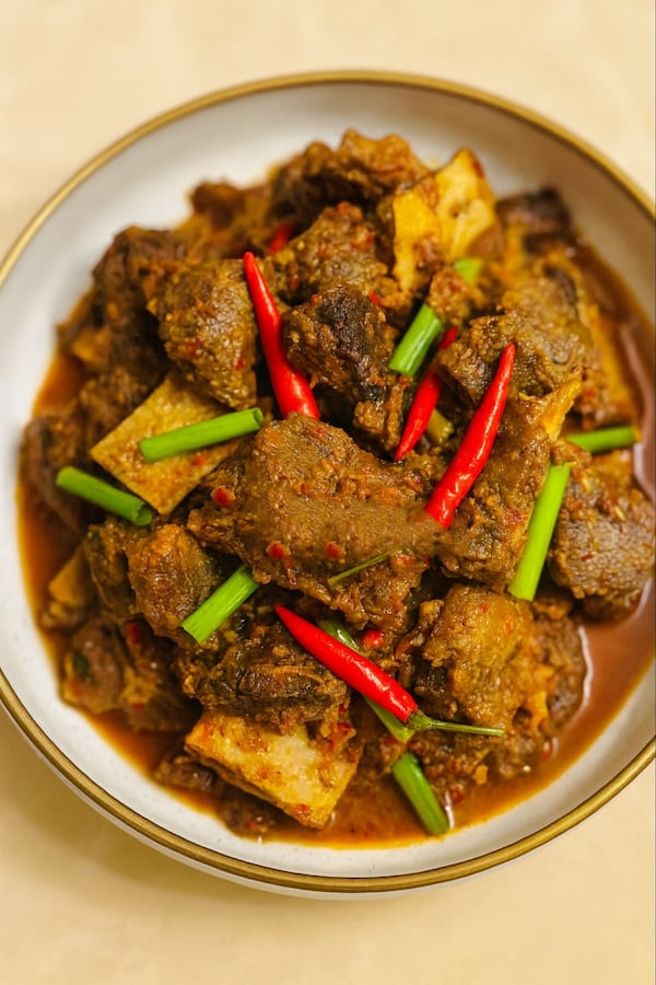 Plate of braised meat with red chiles and green onions.