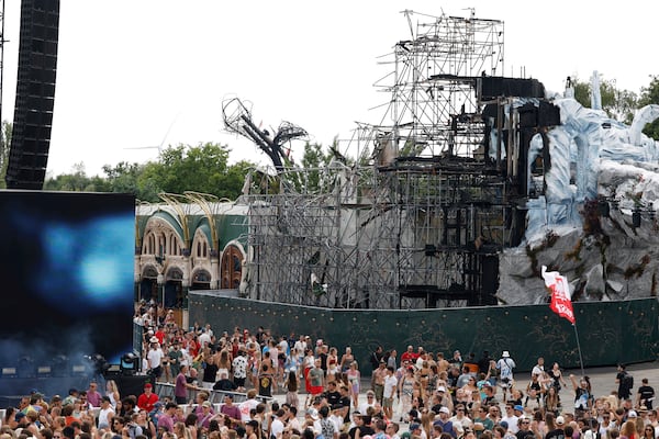 People listen to Odymel B2B and Pegassi, foreground left, performing next to the burned main stage at the Tomorrowland music festival in Boom, Belgium, Friday, July 18, 2025. (AP Photo/Omar Havana)