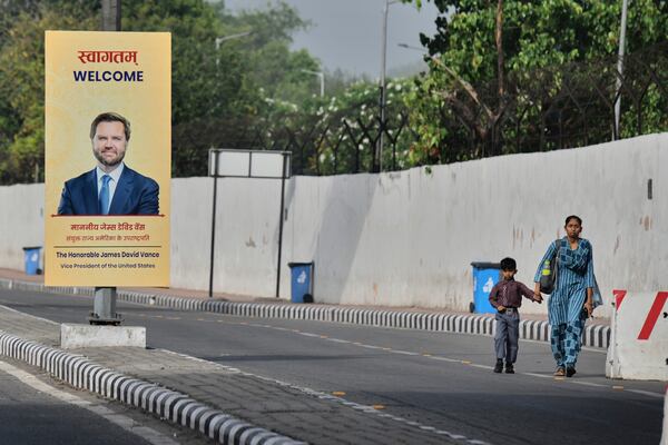 A woman and a child walk past a banner welcoming U.S. Vice President JD Vance on a street in New Delhi, India, Monday, April 21, 2025. (AP Photo)