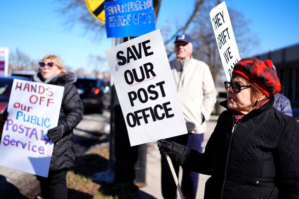 Connie Cameron, right, holds a sign during a demonstration outside of the United States Postal Service in Arlington Heights, Ill., Thursday, March 20, 2025. (AP Photo/Nam Y. Huh)