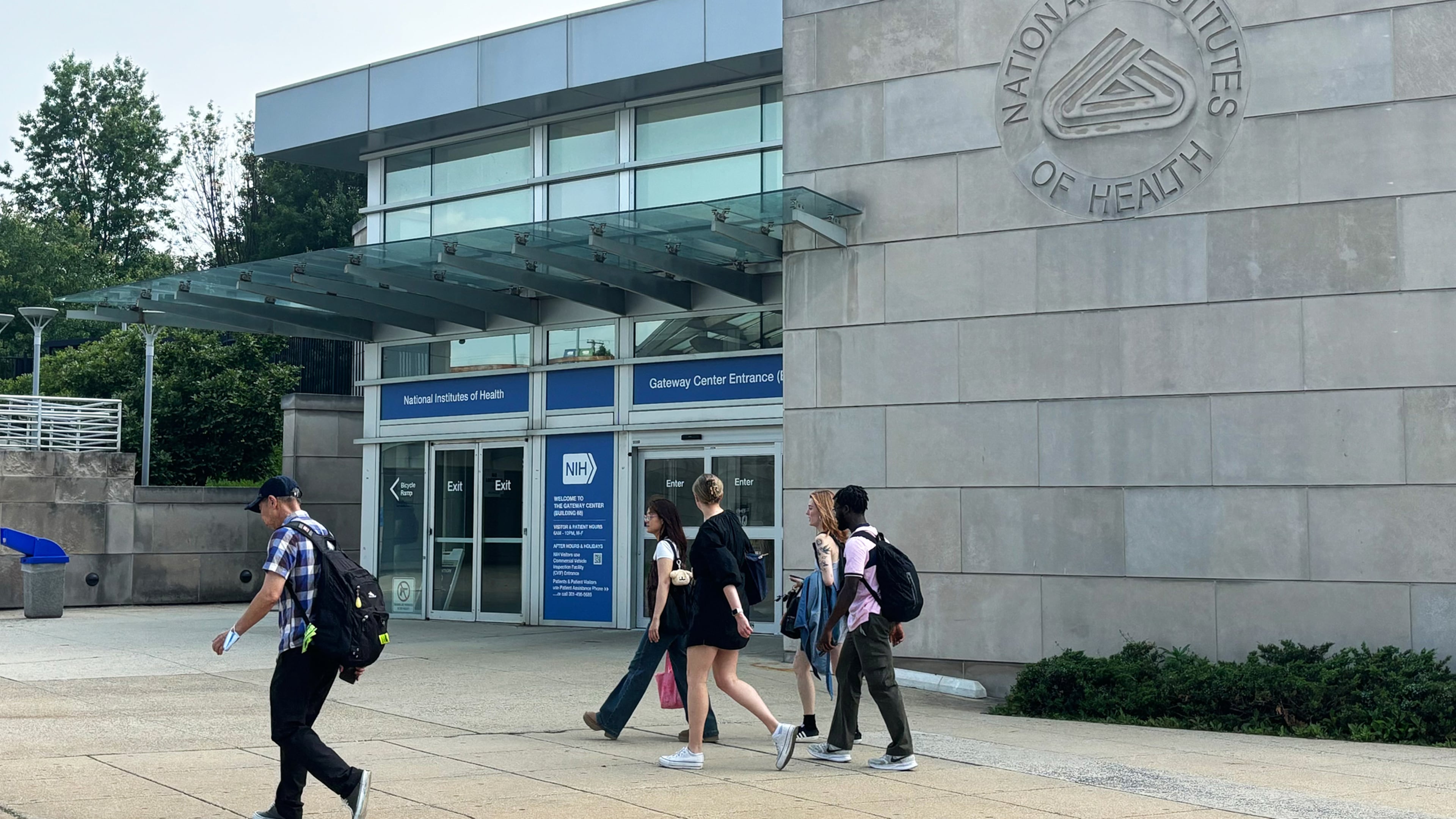 People walk past an entrance to the National Institutes of Health campus in Bethesda, Maryland, on June 5, 2025. (Eric Harkleroad/KFF Health News/TNS)