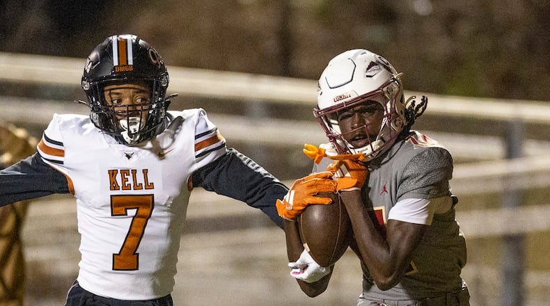 Creekside wide receiver Armani Hill (right) makes a catch while Kell defensive back Robert Tyson Jr. tries to intercept during the Class 4A semifinals last season. Both teams are playing in a higher class this season. (Oscar Guevara Saenz for the AJC)