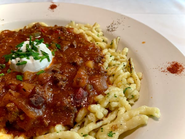The goulash at Kurt’s Euro Bistro is served over spaetzle noodles and with a dollop of sour cream. (Christopher Hassiotis for the AJC)