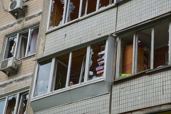 A resident looks out of the broken window in an apartment house following Russia's drone attack in Kyiv, Ukraine, Sunday, May 4, 2025. (AP Photo/Efrem Lukatsky)