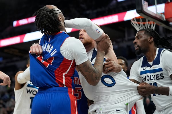 Detroit Pistons forward Ronald Holland II (00) left, and Minnesota Timberwolves guard Donte DiVincenzo, middle, fight during the first half of an NBA basketball game, Sunday, March 30, 2025, in Minneapolis. (AP Photo/Abbie Parr)