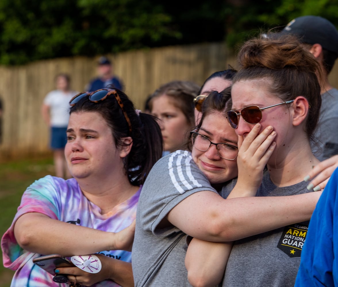 Members of the Holly Springs community and neighboring police departments gather at Barrett Park for a candlelight vigil for Police Officer Joe Burson on Friday, June 18, 2021 after he was killed during a traffic stop earlier this week.  Coworkers and friends of Marykate Burson, Joe’s wife, including Katie Beganovic, left, and sisters Gina and Angela Ruggiero gather to mourn their friend’s husband.  The Ruggiero sisters have know Marykate since middle school.  (Jenni Girtman for The Atlanta Journal-Constitution)