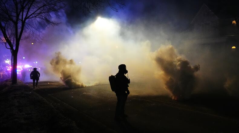 Law enforcement officers stand amid tear gas at the scene of a reported shooting Wednesday, Jan. 14, 2026, in Minneapolis. (AP Photo/Adam Gray)