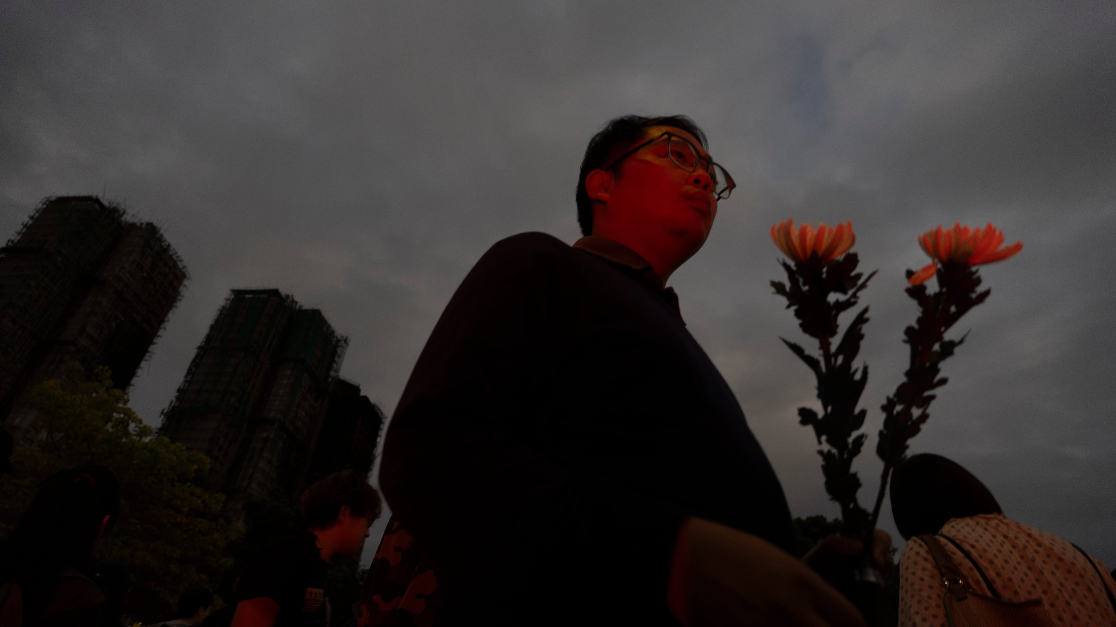 A man holding flowers arrive at the site of a deadly fire at Wang Fuk Court, a residential estate in the Tai Po district of Hong Kong's New Territories, on Tuesday, Dec. 2, 2025. (AP Photo/Ng Han Guan)