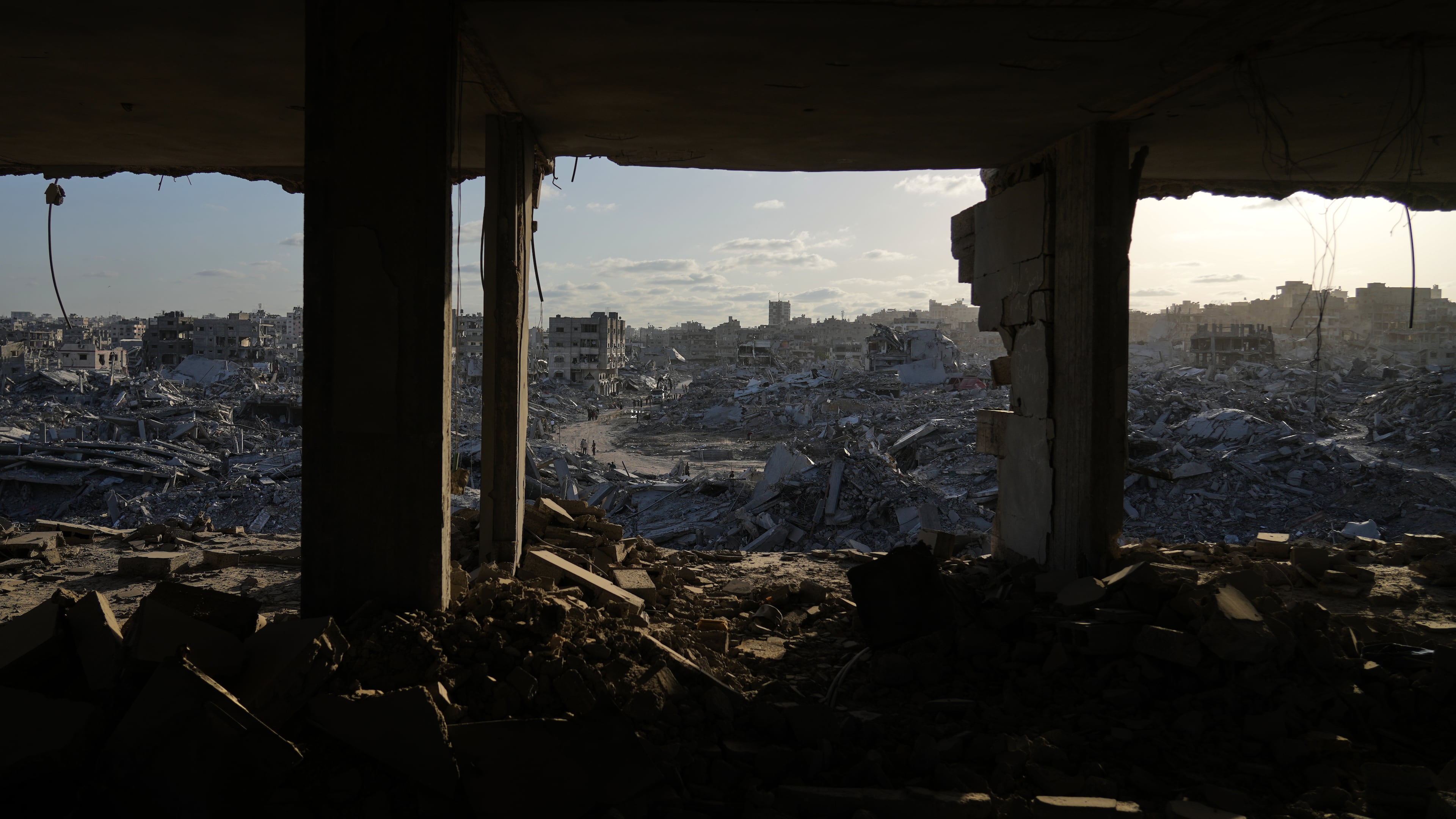 Displaced Palestinians walk amid destroyed buildings in the heavily damaged Sheikh Radwan neighborhood in Gaza City, Saturday, Oct. 11, 2025, after Israel and Hamas agreed to a pause in their war and the release of the remaining hostages. (AP Photo/Abdel Kareem Hana)