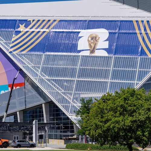 There are no plans to close streets around Mercedes-Benz Stadium — seen here getting new signage earlier this month — or Centennial Olympic Park during the World Cup, Atlanta police said. (Ben Hendren for the AJC)