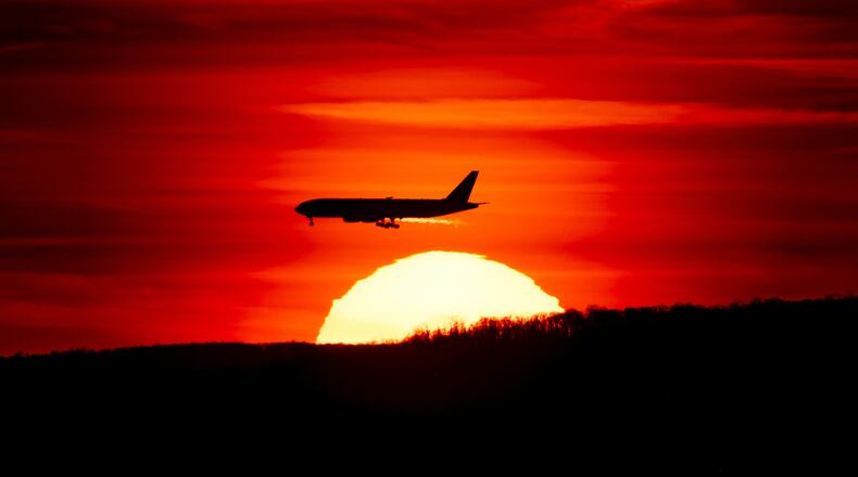 FILE - A passenger jet on approach to Newark Liberty International Airport flies over the setting sun in Newark, N.J., March 27, 2019. (AP Photo/J. David Ake, File)