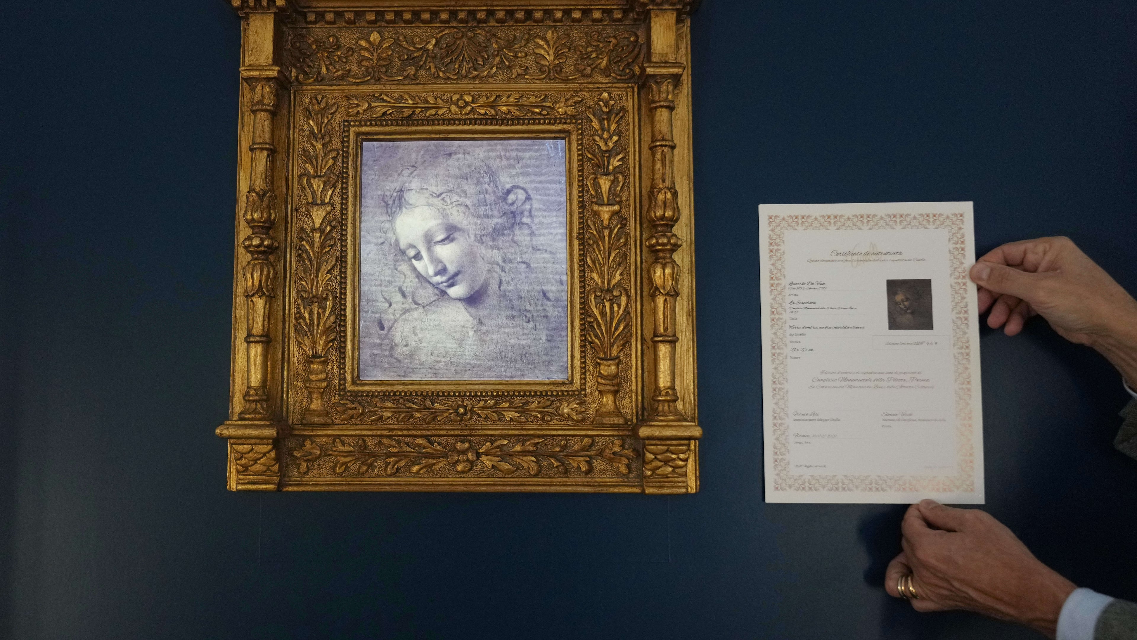 Primo Maronati holds a certificate next to a digital version of Leonardo Da Vinci's portrait, "La Scapiliata, Lady with Disheveled Hair," at the Brera Art Gallery in Milan, Italy, Monday, Nov. 24, 2025. (AP Photo/Antonio Calanni)