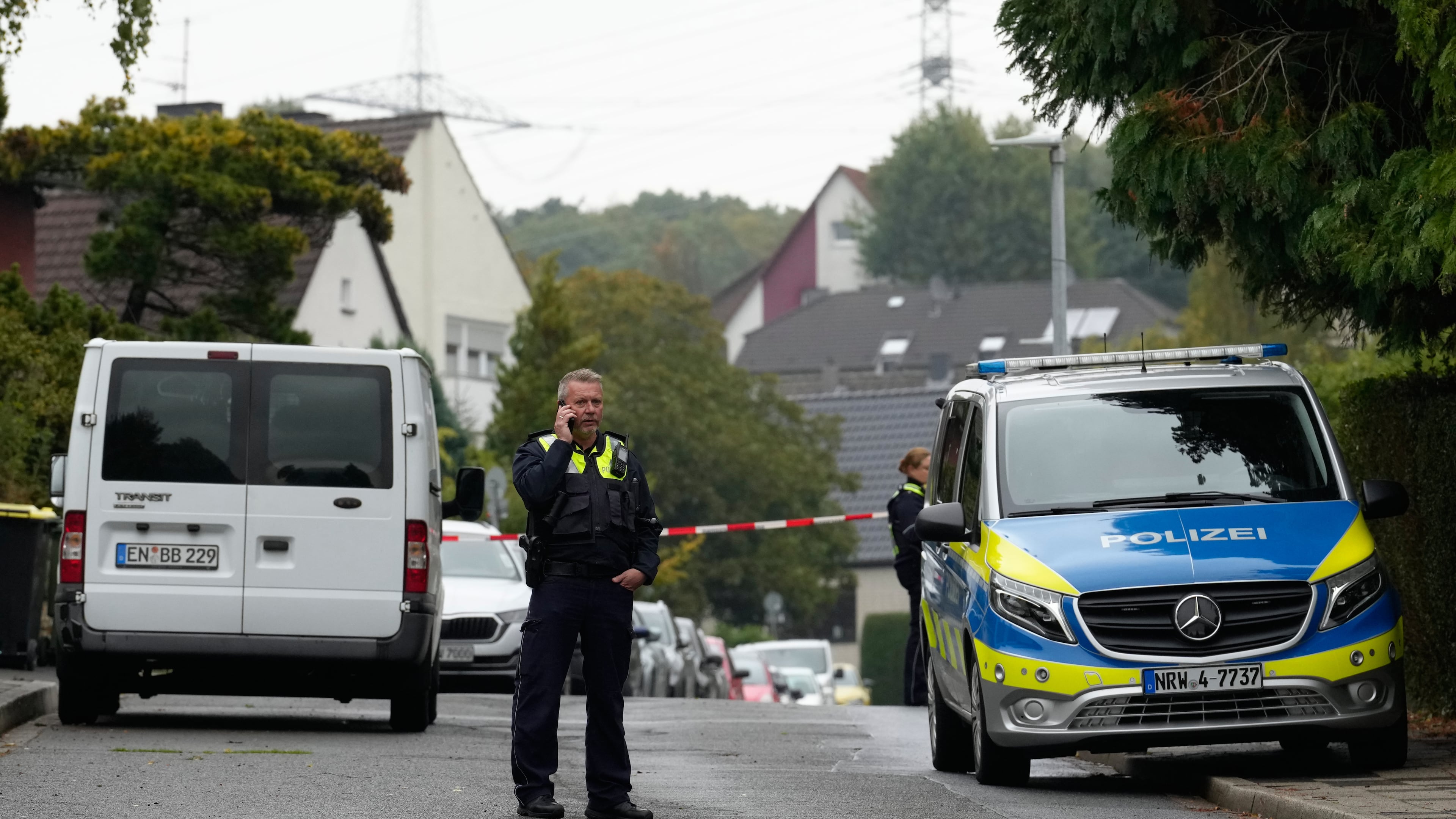 A police officer talks on his phone at a street in Herdecke, Germany, Tuesday, Oct. 7, 2025, after the newly elected mayor of Herdecke, Iris Stalzer, has been found critically injured in her apartment. (AP Photo/Martin Meissner)
