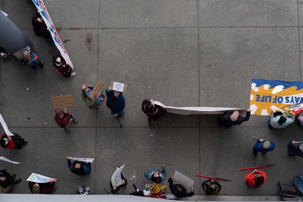 People hold signs during a protest outside the annual Alaska Sustainable Energy Conference on Tuesday, June 3, 2025, in Deadhorse, Alaska. (AP Photo/Jenny Kane)
