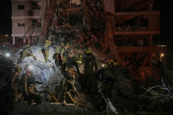 Israeli security forces inspect destroyed buildings that were hit by a missile fired from Iran, near Tel Aviv, Israel, Sunday, June 15, 2025. (AP Photo/Ohad Zwigenberg)