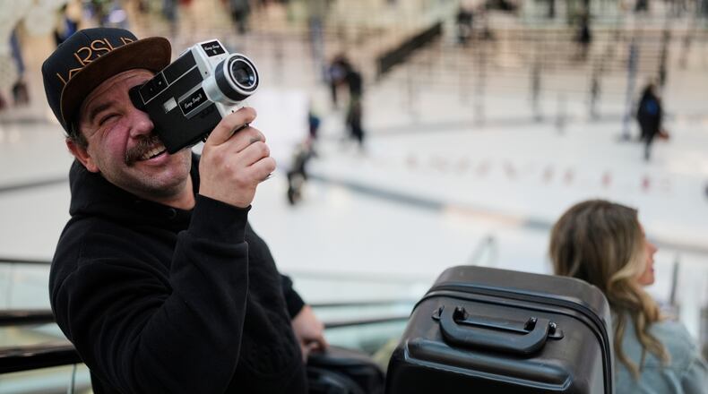 Jordan Heid uses an old film camera as he arrives for his flight at the Nashville International Airport, Tuesday, Nov. 25, 2025, in Nashville, Tenn. (AP Photo/George Walker IV)