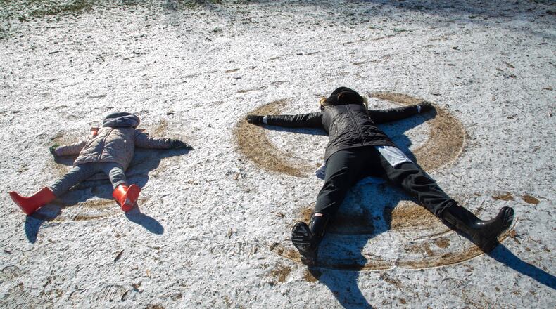 Amelia Walton and her daughter Irene Walton-Hines, 3, try to make snow angels in the light dusting of snow at Piedmont Park on Saturday, January 29, 2022. STEVE SCHAEFER FOR THE ATLANTA JOURNAL-CONSTITUTION