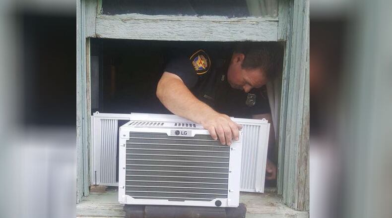 Fort Worth Police officer William Margolis helps install a new air conditioner unit in the home of 95-year-old Julius Hatley.
